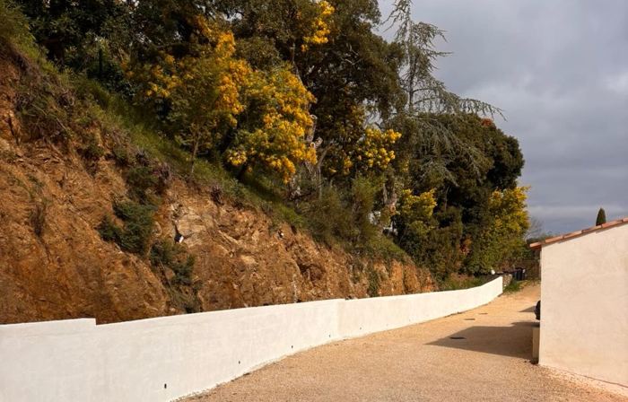 Long mur de clôture enduit en blanc le long d’une allée
